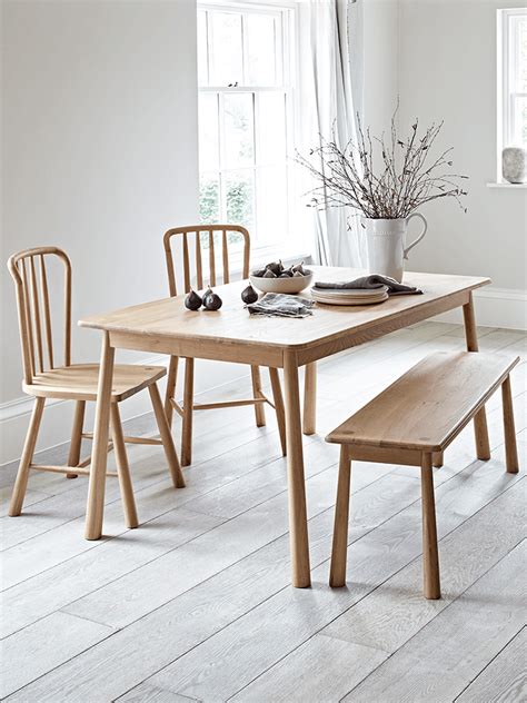 A Dining Table With Two Chairs And A Bench In Front Of The Window Next