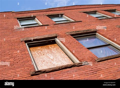 Exterior Wall Of A Brick Office Building With One Window Boarded Up