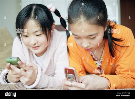 Close Up Of Two Sisters Using Mobile Phones Stock Photo Alamy