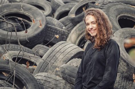 Premium Photo Cheerful Curly Haired Girl Standing Against A Landfill