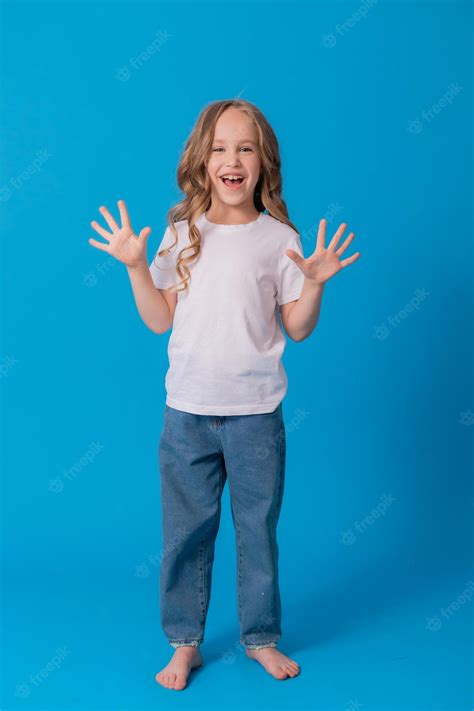 premium photo portrait of a curly haired girl in jeans and a white t shirt on a blue background
