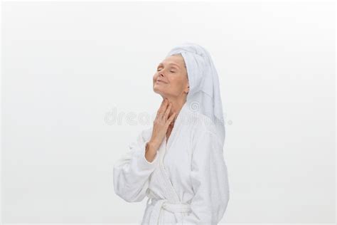 feminine adult older woman wearing bathrobe and towel over her head smiling isolated over white