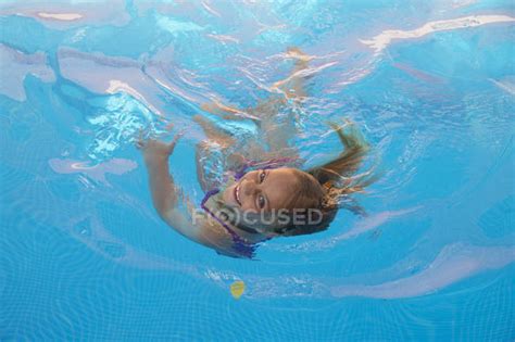Дети плавают в бассейне с бирюзовой водой и смотрят в камеру — Вода
