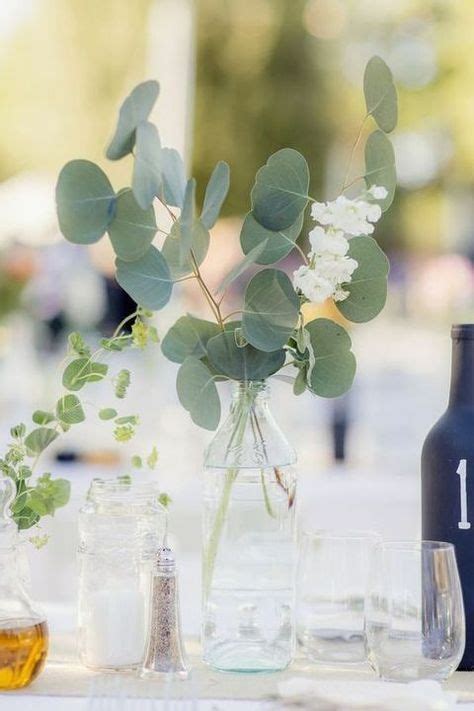 The Table Is Set With Glasses Bottles And Flowers In Vases That Are On