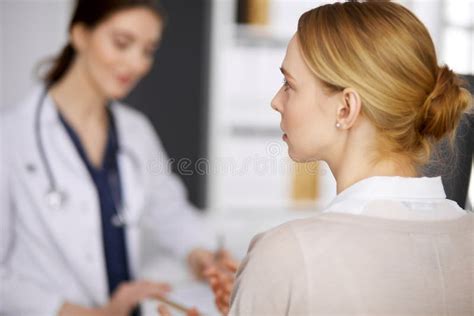 Friendly Smiling Female Doctor And Patient Woman Discussing Current
