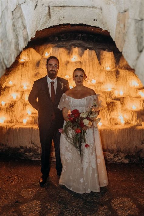 Bride And Groom Portrait In A Limestone Cave Surrounded By Candles