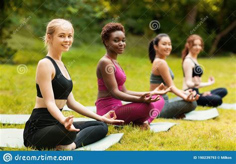 Diverse Women Attending Yoga Class At Park Sitting In Lotus Pose Outside Empty Space Stock