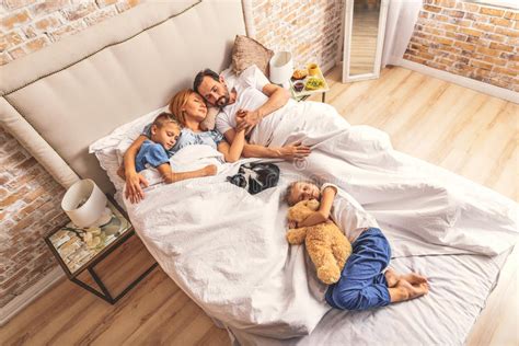 Familia Que Duerme Junto En Cama Foto De Archivo Imagen De Cuidado