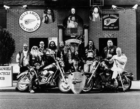 A Group Of People Sitting On Motorcycles In Front Of A Brick Building