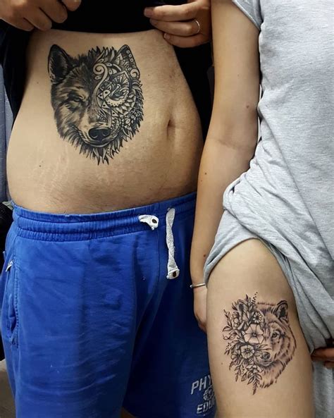 Two People Standing Next To Each Other With Tattoos On Their Stomachs