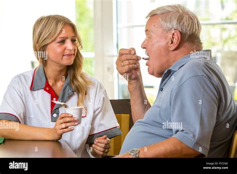 Elderly Care In A Nursing Home Nurse Helps An Elderly Man Eating His