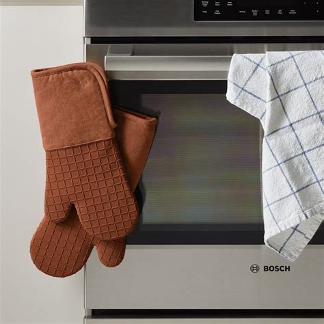 Two Oven Mitts Sitting On Top Of An Oven Door Next To A Dish Towel