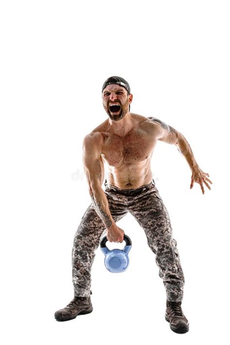 Muscular Athlete Bodybuilder Man In Camouflage Pants With A Naked Torso Workout With Kettlebell