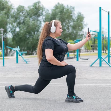 A Beautiful Fat Girl In Headphones Is Engaged In Fitness On The Sports
