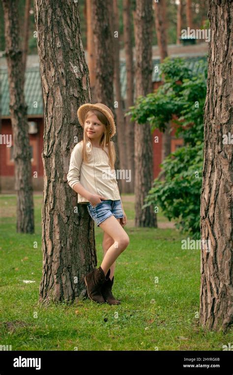 Dreamy Tween Girl Leaning Against Tree In Green Summer Courtyard Of