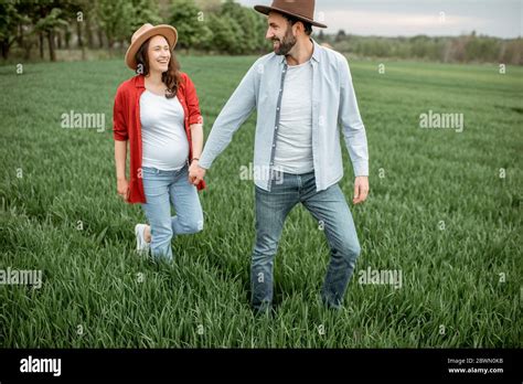 Pregnant Woman With Her Man Having Fun Together Walking On The Greenfield Happy Couple