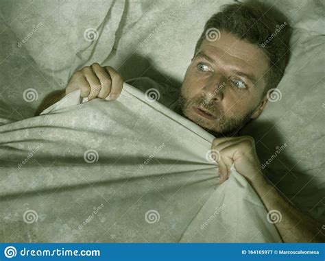 Stressed And Scared Man Alone In Bed Awake At Night In Fear After