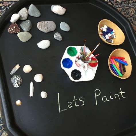 A Black Tray With Rocks Paints And Pencils On It That Says Let S Paint