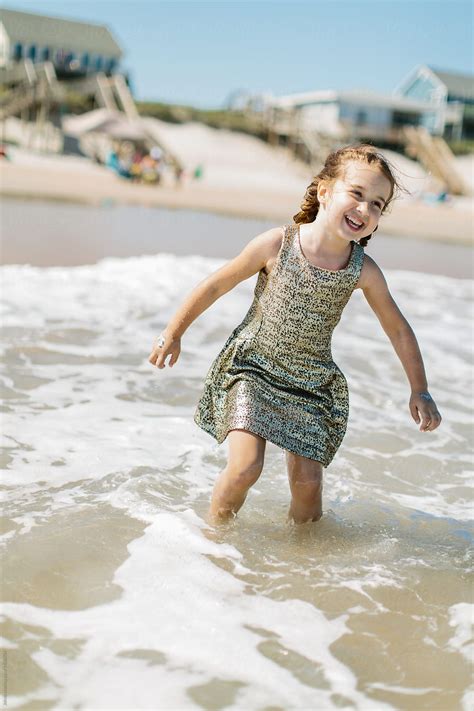 Cute Young Girl Wearing Fancy Gold Dress Playing In The Ocean By
