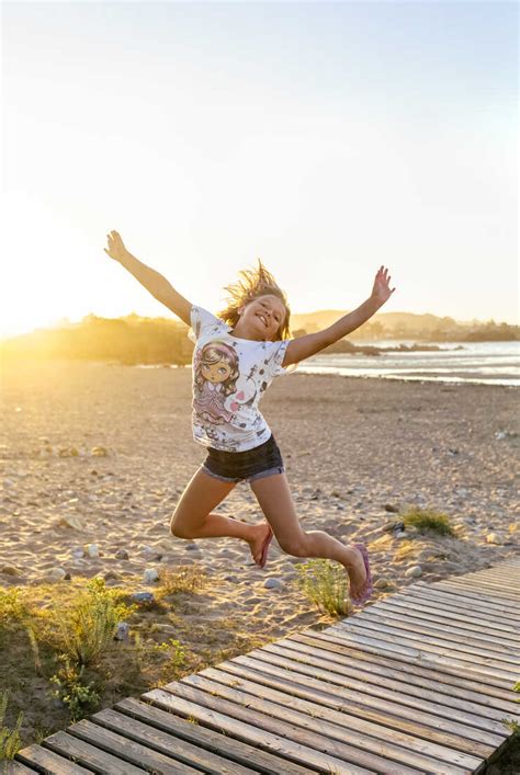 Portrait Of Smiling Girl Jumping In The Air On The Beach