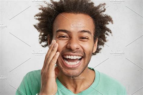 Headshot Of Shy Dark Skinned Male With Crisp Hair Smiles Broadly