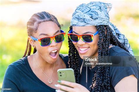 Afrolatinx Playful Young Lesbians Embracing In A Park Taking Selfies With Their Smart Phone