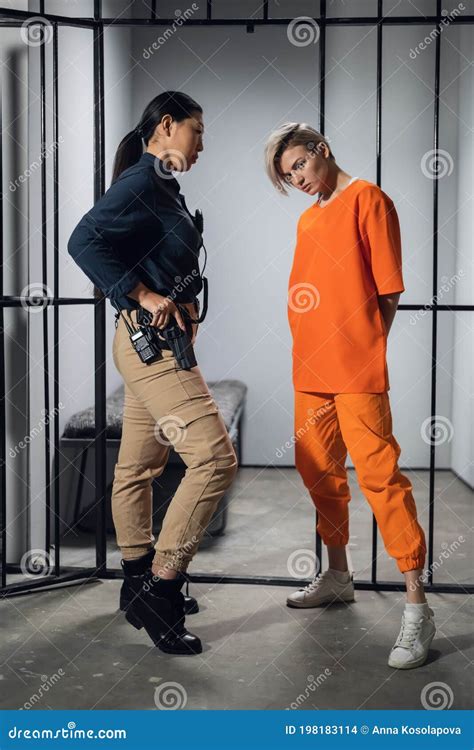 Asian Warden And A Female Prisoner In A High Security Prison Stand In Front Of An Open Cell