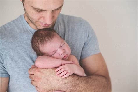 Proud Father Holding His Newborn Son Gently In His Arm By Stocksy Contributor Lea Csontos