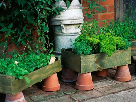 Three Wooden Planters Filled With Green Plants On Top Of A Brick Floor