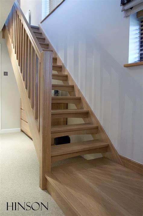 A Wooden Stair Case Next To A Window In A Room With White Walls And Carpet