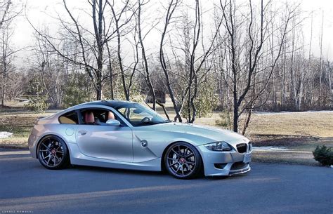 A silver sports car parked in front of some trees