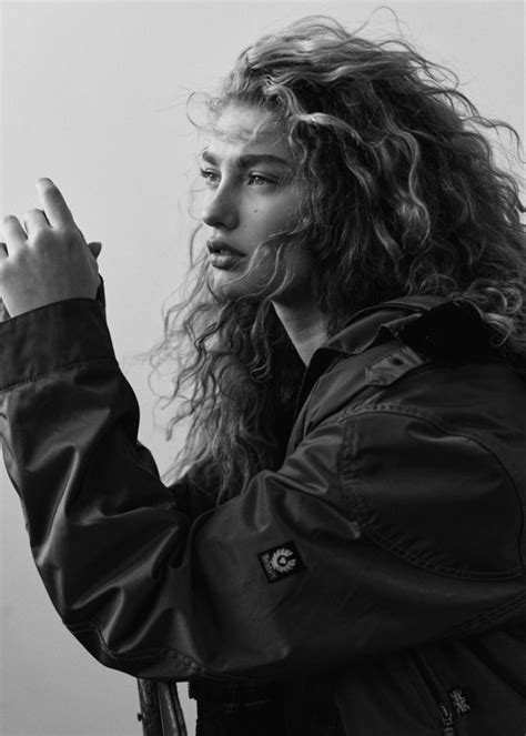 A Black And White Photo Of A Woman With Curly Hair Holding A Cell Phone