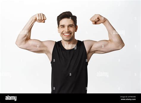 Sport And Gym Smiling Young Healthy Man Flexing Biceps Showing Strong Big Muscles And Fit Body