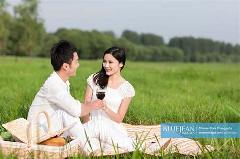Cheerful Young Chinese Couple Having A Picnic On The Grass High Res