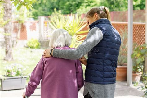 Professional Young Helpful Caregiver Walking With The Elderly Woman In