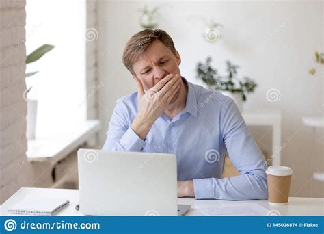 Tired Businessman Yawning At Workplace Near Laptop Stock Photo Image