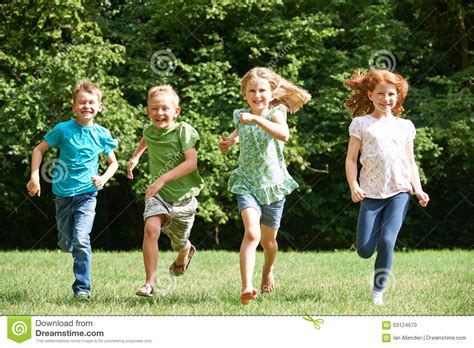 Group Of Children Running Towards Camera In Playground Stock Photo
