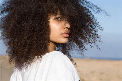 Young Black Woman With Curly Hair In Barren Landscape By Stocksy