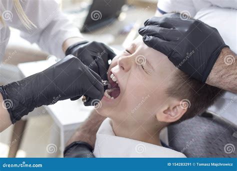 Child With A Grimace Of Pain On The Face Is Sitting On A Dental Chair