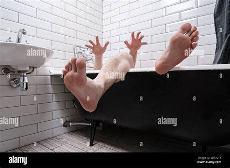 Wet Male Legs And Hands With Spread Fingers Are Visible From The Cast Iron Bathtub In The Modern