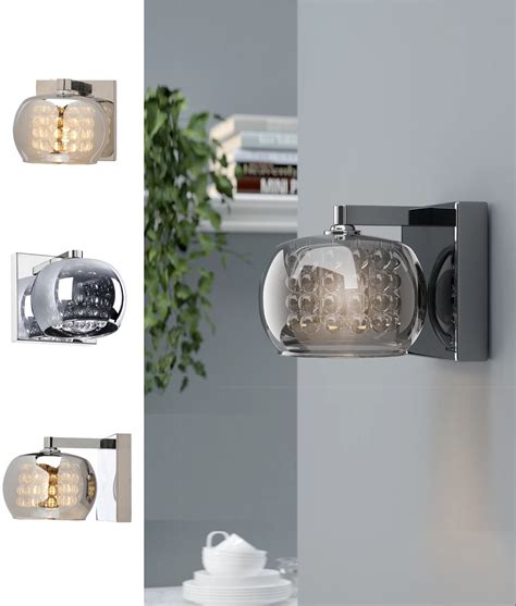 Compact luminaires direct light down from the pure geometry of a triangular prism. A contemporary compact wall light, made to shimmer and ...