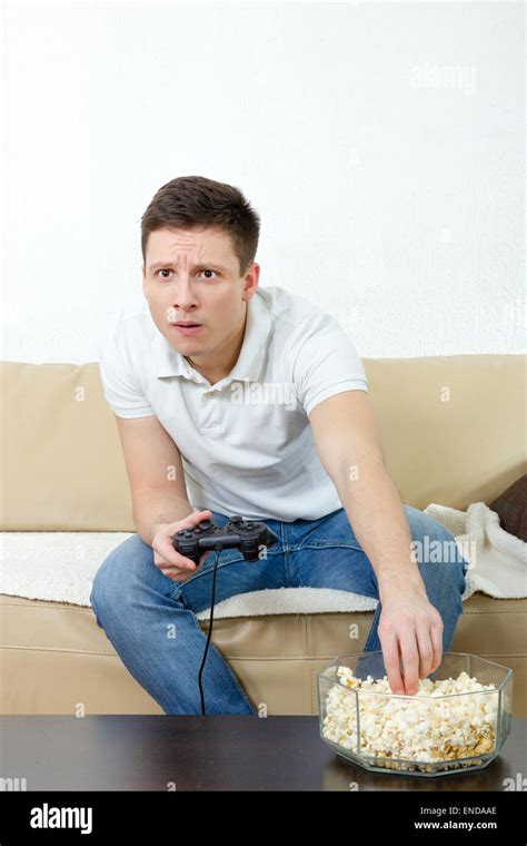Focused Man Playing Video Game Holding Joystick And Eating Popcorn