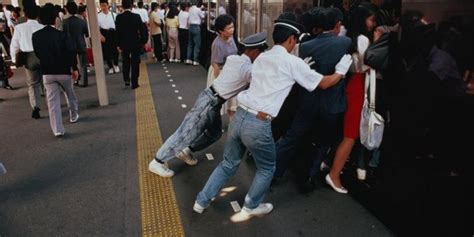 Several People Are Standing On The Side Of A Train Platform With Their Arms Around Each Other