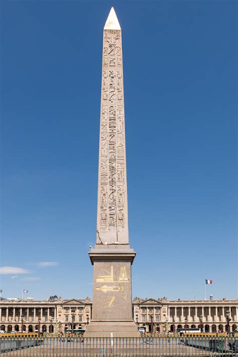 The Obelisk Stands In Front Of An Old Building With Writing On Its Sides