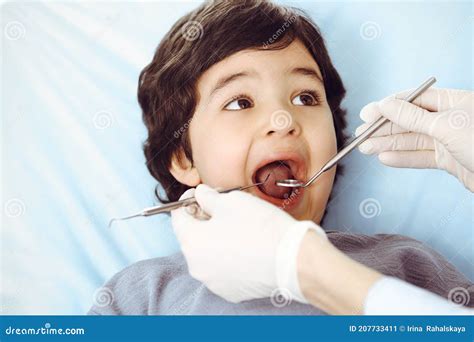 Cute Arab Boy Sitting At Dental Chair With Open Mouth During Oral