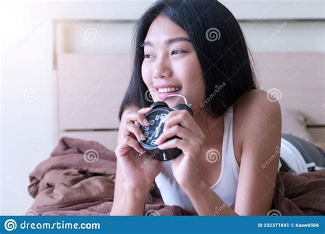 Woman Waking Up Holding Alarm Clocks On The Bed In The Morning Lifestyle Concept Stock Image