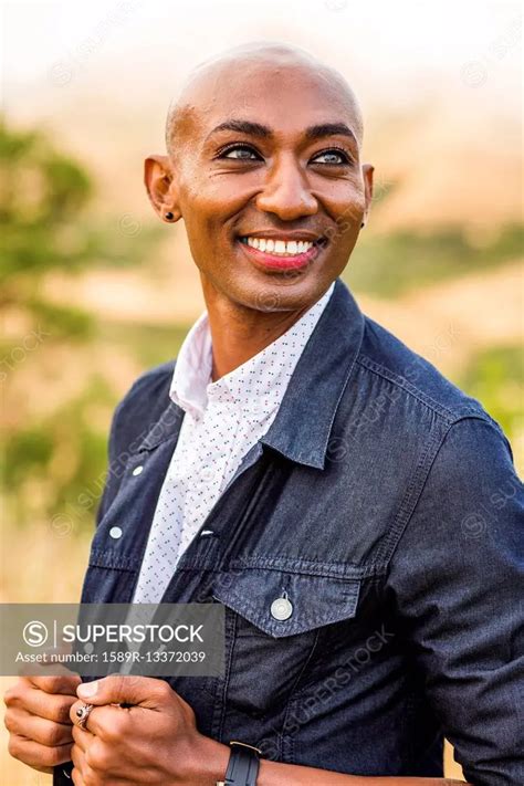 smiling gay black man holding denim jacket superstock