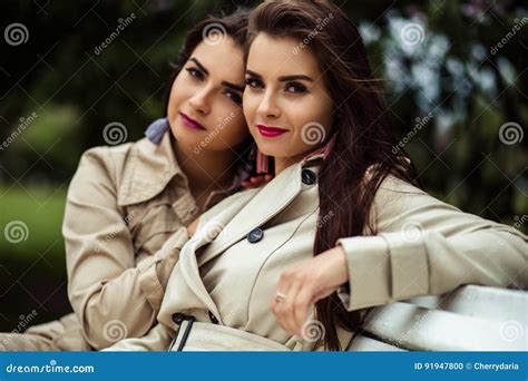 2 красивых молодой женщины близнецов в сирени пальто канавы близко зацветая Стоковое Фото