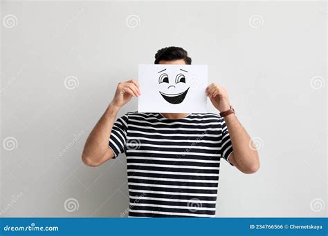 Man Hiding Emotions Using Card With Drawn Smiling Face On White