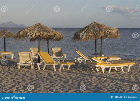 Summer Sun Beds And Umbrellas On Sandy Greece Beach At Evening Seaside With Parasols Stock